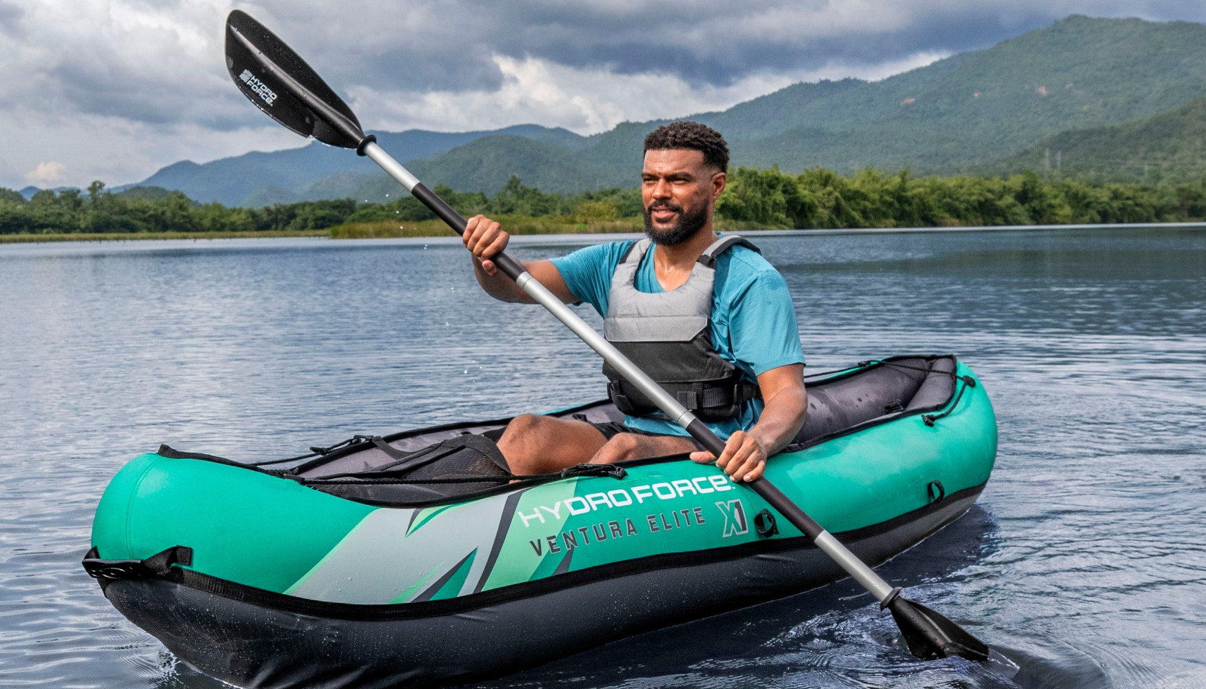 Close-up of a man in an inflatable kayak with a mountain landscape in the background